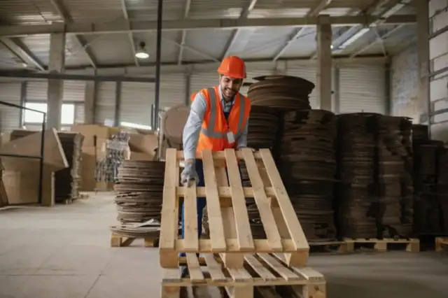 Worker handling a wooden pallet in a warehouse